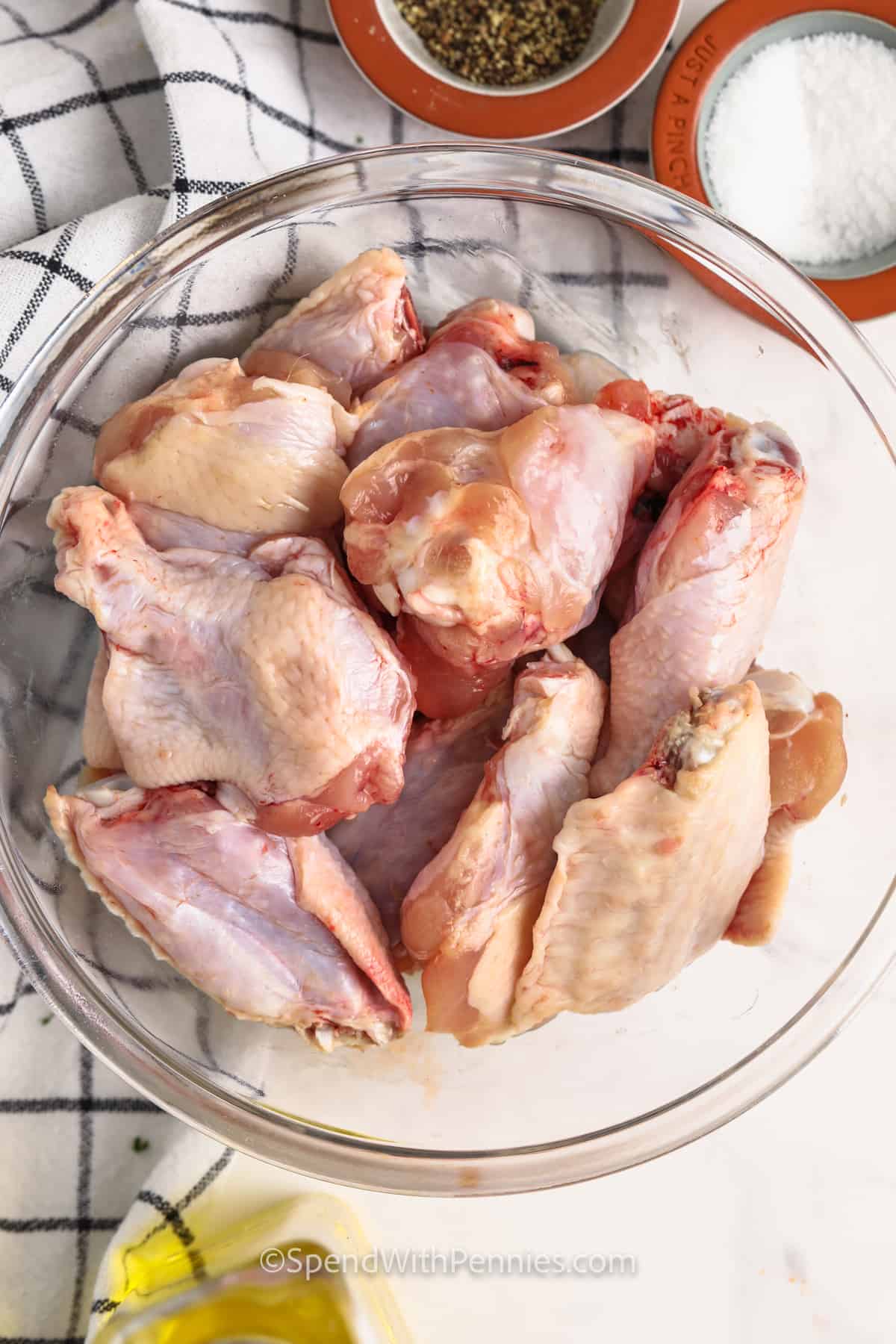 chicken wings in a bowl with salt , pepper and oil beside it to make Air Fryer Chicken Wings