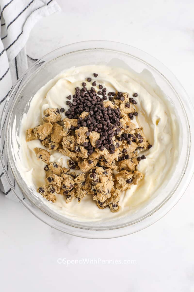 adding cookie dough and chocolate chips to a bowl for cookie dough ice cream