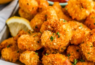 crispy popcorn shrimp on a tray with lemon and cocktail sauce