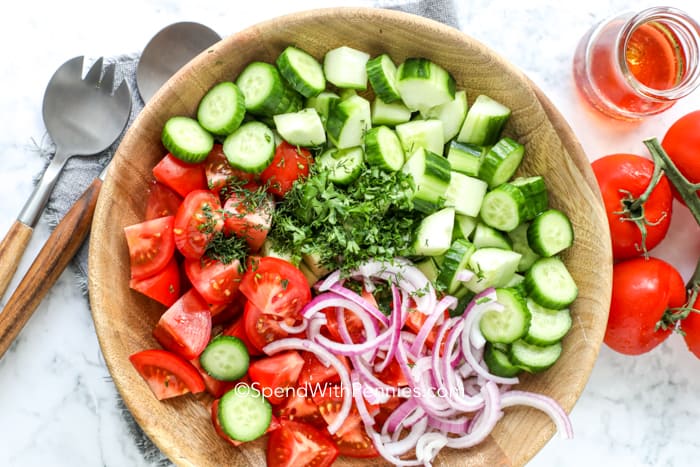 Overhead shot of Cucumber Tomato Salad ingredients in a bowl before mixing together