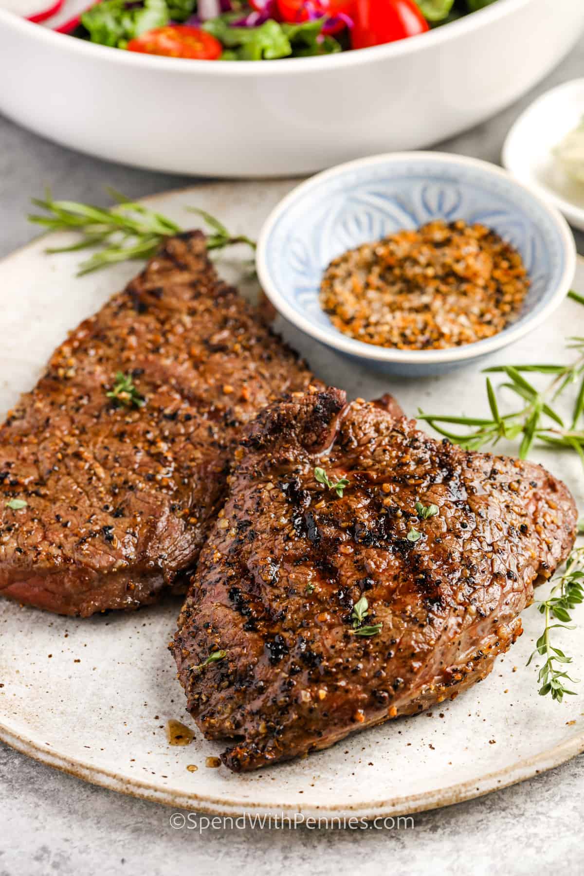 Grilled Sirloin Steak on a plate with a bowl of salad