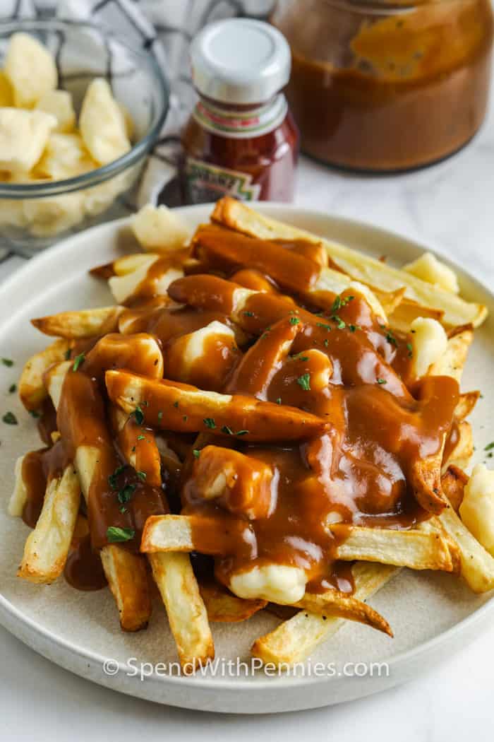 plated Poutine with ketchup gravy and cheese curds in the back
