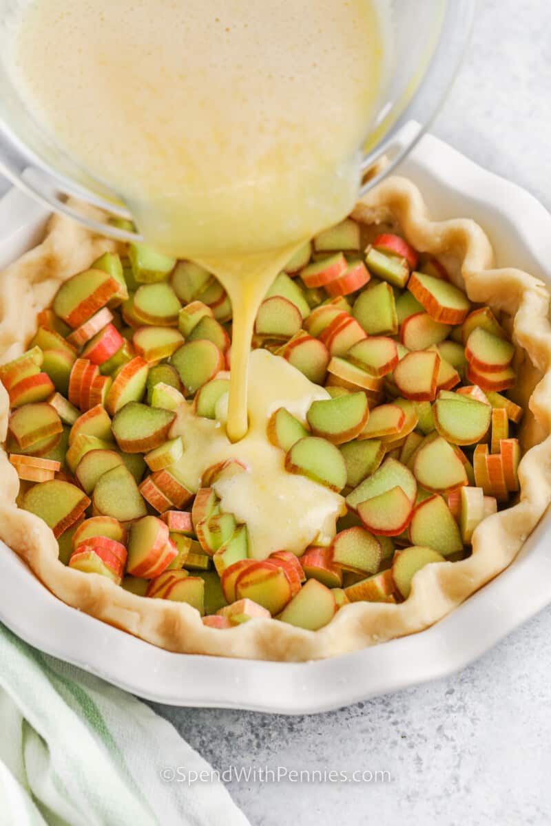 pouring custard into rhubarb to make Rhubarb Custard Pie