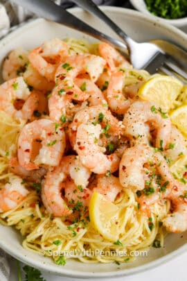 Shrimp Scampi in a bowl with lemon slices and fork