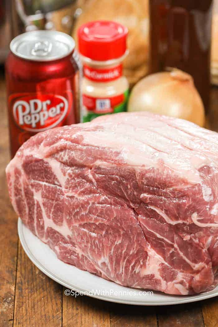 Pork on a plate with can of Dr. Pepper, onion and spices in the background