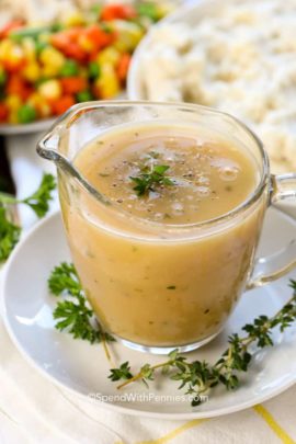 Turkey gravy in a clear glass pouring cup on a white plate