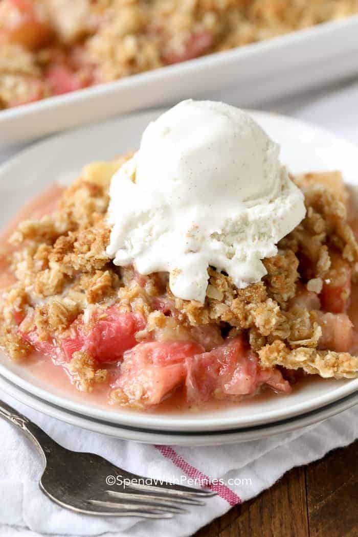 With a perfect balance between sweet and tart, Rhubarb Crisp is a delicious, old fashioned dessert prepared in just minutes! This easy Rhubarb Crisp is a delicious and easy dessert you can make in minutes! With the perfect balance between sweet and tart, rhubarb crisp is going to be your new summer favorite. #spendwithpennies #easyrecipe #easydessert #rhubarbcrisp #strawberryrhubarb #withoatmeal #bakedrecipe #fruitcrisp Rhubarb Crisp served à la mode on a white plate
